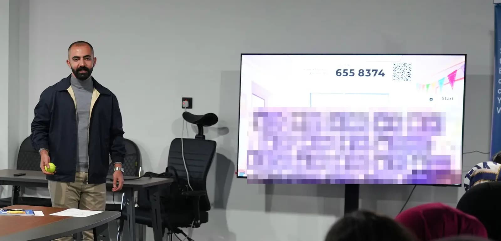 Aland presenting to a room, with a quiz on the screen behind him